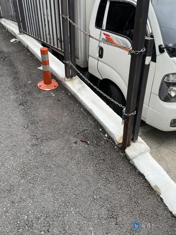 탄력봉 한 개만 남아 있는 주차장 입구와 연석
