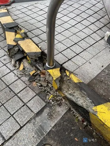 차량 충돌로 조각나 부서진 주차장 출입구 경계석과 드러난 가드레일 기둥 밑동
