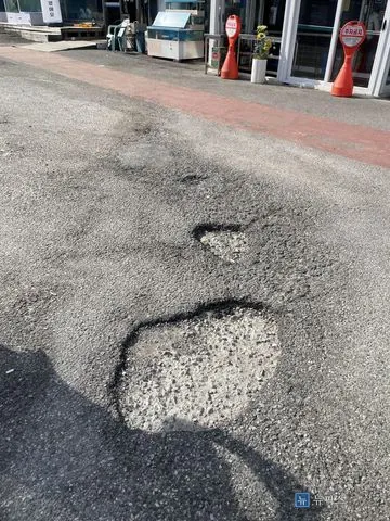 표면이 깨지고 골재가 드러난 마트 앞 아스콘 파손부