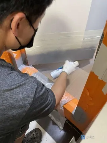 스프레이 캔으로 방화문 하단에 도장 작업 중인 작업자