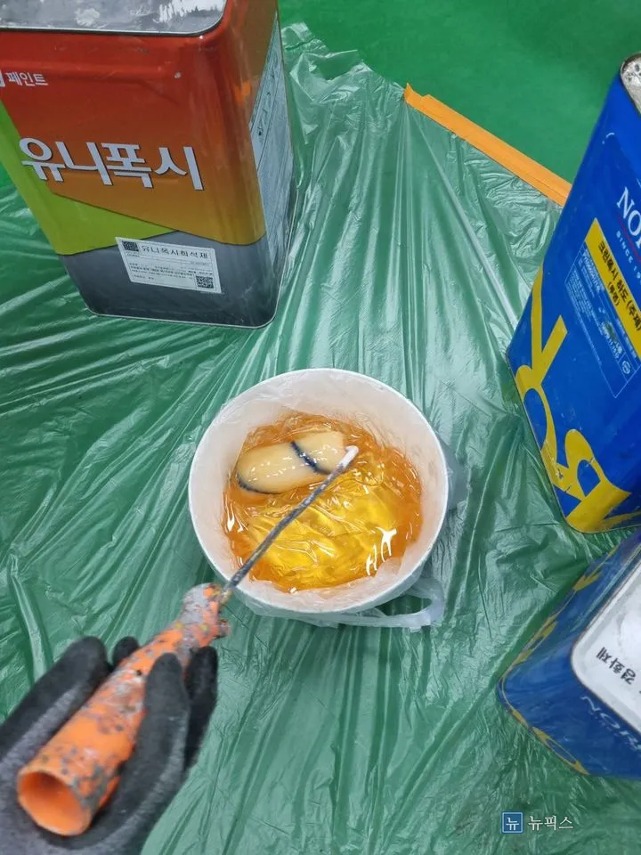 에폭시 희석제와 프라이머 통을 놓고 배합 중인 도료
