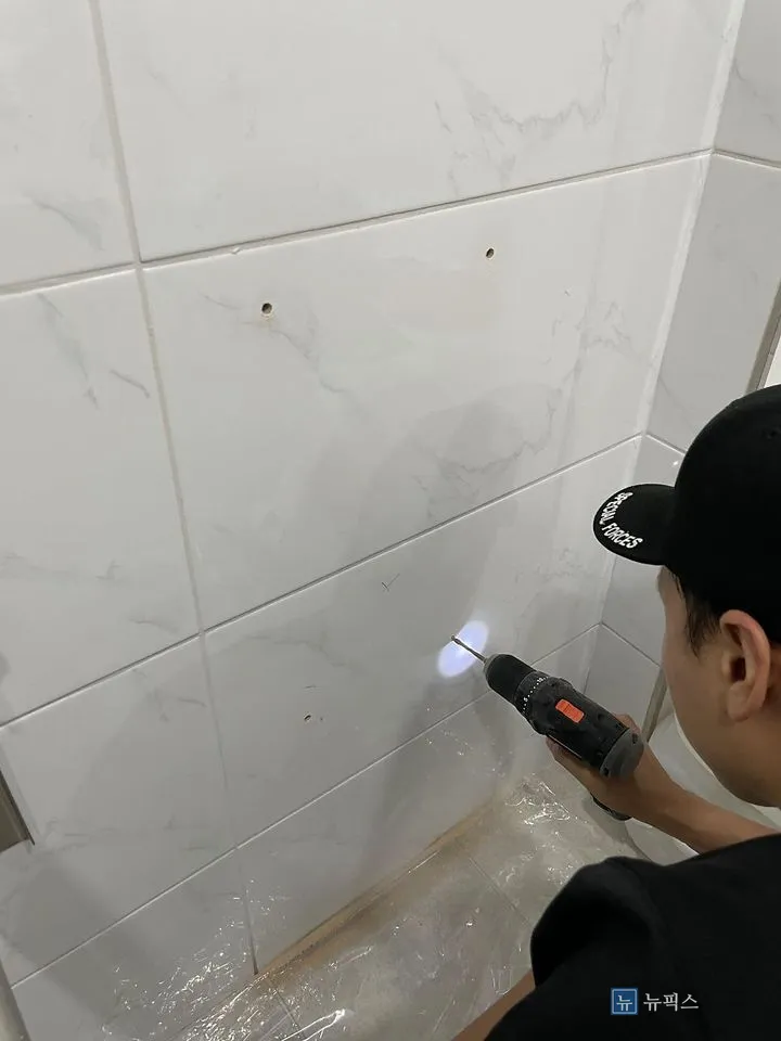 타일 벽면에 드릴로 타공 작업을 하는 모습