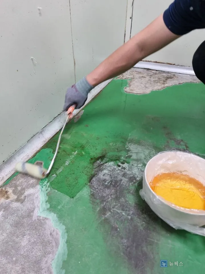 연삭 후 바닥에 롤러로 프라이머를 도포하는 작업 모습