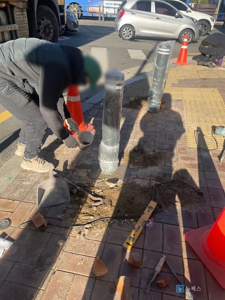 매립한 볼라드 주변에 시멘트를 채우고 수평계로 확인하는 작업