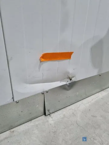 철제 몰딩 위쪽이 움푹 들어가고 철판이 찢어진 샌드위치 판넬 벽