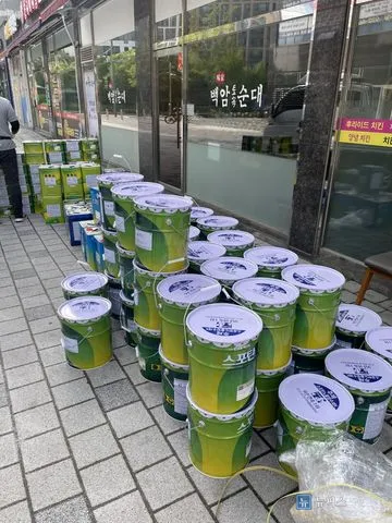 상가 앞 인도에 쌓아둔 우레탄 방수 페인트 캔과 자재
