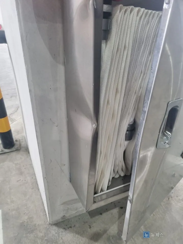 벌어진 소화전함 문 틈으로 호스가 비어져 나온 모습