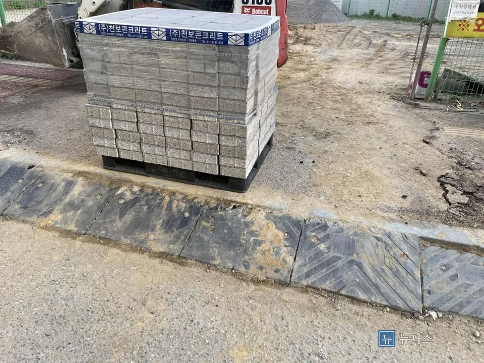 경계 부분에 놓인 기존 고무 경사판과 팔레트에 쌓인 보도블럭
