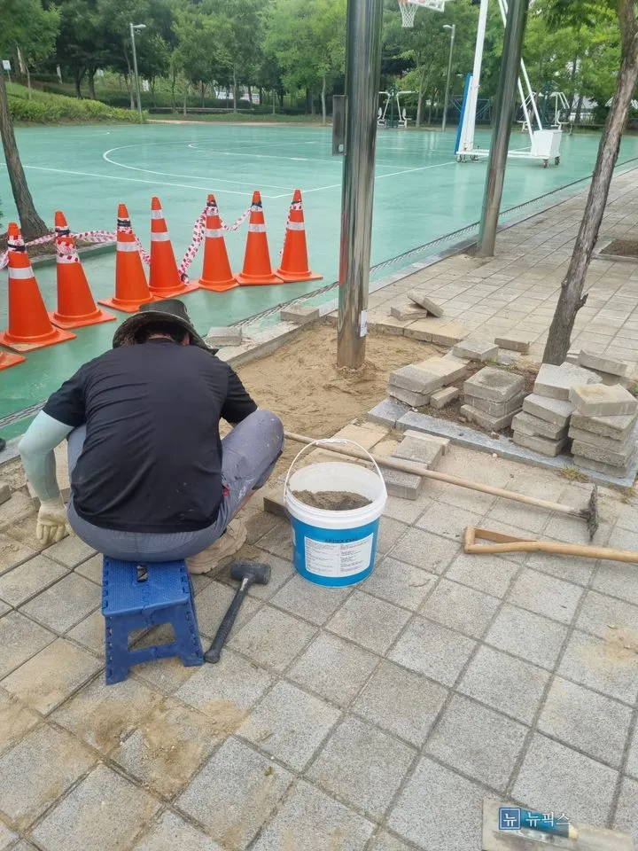 작업자가 앉아 모래 높이를 잡으며 블럭 자리를 정리하는 모습