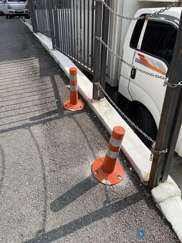 설치를 마친 고무 탄성볼라드 두 개가 경계석을 따라 서 있는 모습