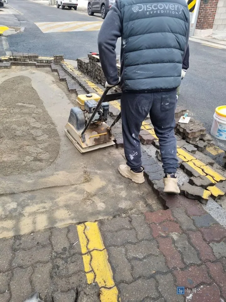 보도블럭을 걷어낸 자리에서 콤팩트로 지반을 다지는 작업자