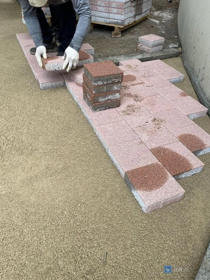모래층 위에 분홍색 보도블럭을 한 장씩 놓는 모습